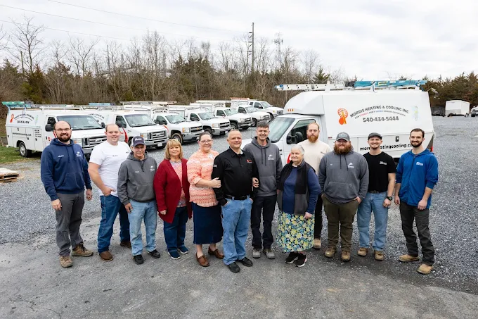 The Morris Heating & Cooling team standing together in front of their service trucks